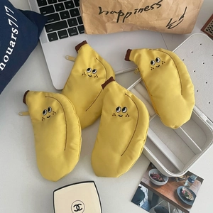 Vue à plat de quatre porte-monnaie banane en toile jaune avec broderie emoji mignonne