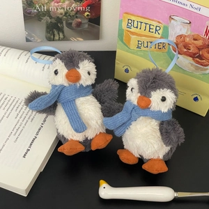 Close-up of cute plush penguin pendants with blue scarves and silk hanging loops