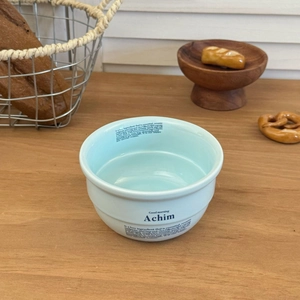 Détail d'un bol en céramique bleu clair avec typographie chic dans un décor de petit déjeuner