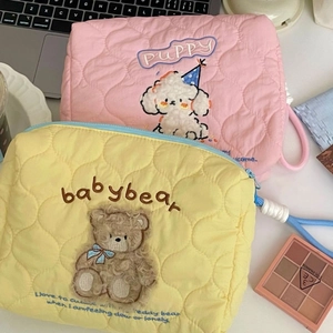 Quilted makeup bag with cute dog and bear embroidery on a desk with a laptop