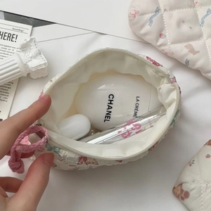 Close-up of quilted floral coin purse showing interior storage for lipstick and creams