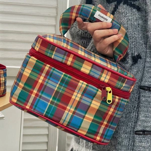 Detail of multi-color plaid makeup bag with sturdy handle and dual zipper closure