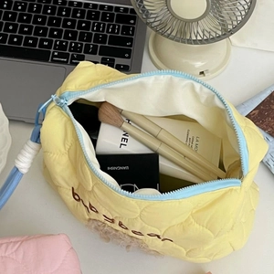 Quilted yellow makeup bag with blue zipper and bobobear embroidery on desktop