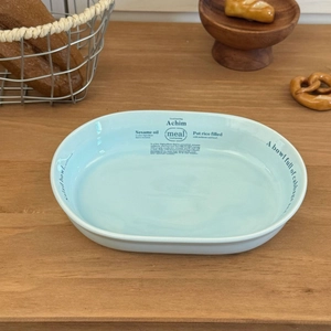 Vue de dessus d'un bol à salade ovale en céramique bleu clair avec typographie sur bois