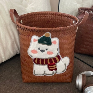 Detail of a brown woven storage basket featuring a cute cartoon dog embroidery and leather handles