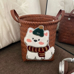 Close-up of brown woven storage basket featuring a cute cartoon cat patch and leather handles