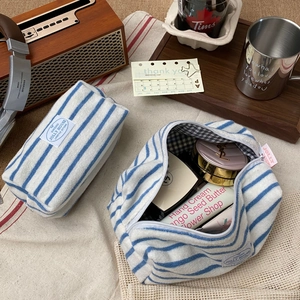 Detail view of blue striped terry cloth cosmetic bags with checkered lining and soft texture