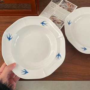 Detail of vintage ceramic dessert plate featuring blue swallow pattern on retro wooden table