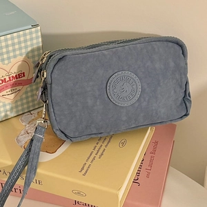 Détail d'une pochette en tissu bleu gris à trois fermetures éclair avec dragonne