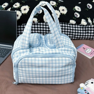 Detail view of blue checkered makeup bag with multiple zipper compartments and handles