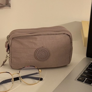 Vue détaillée du portefeuille en nylon lavande avec trois zips et écusson de la marque