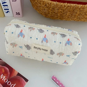 Close-up of white quilted pencil case with blue elephant patterns and top zipper detail
