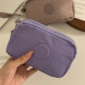 Détail du portefeuille en tissu violet avec logo circulaire et poches à fermetures