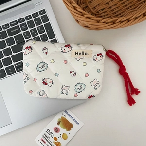 Close-up of white quilted Hello Kitty coin purse with red braided zipper pull on a laptop