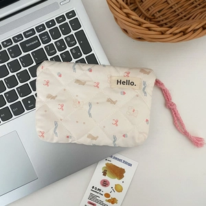 Close-up of quilted floral bear pouch on laptop keyboard with soft natural lighting