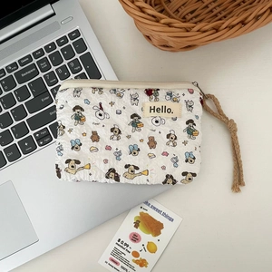 Detail of white quilted coin purse with cartoon dog prints and woven rope zipper pull
