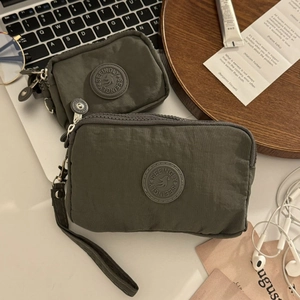 Vue détaillée d'une pochette et d'un porte-monnaie en nylon gris foncé sur un bureau
