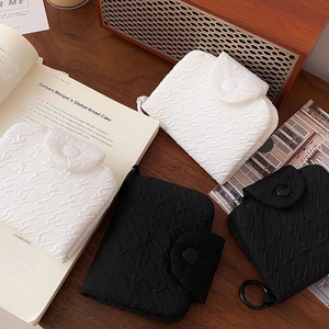 Quilted mini pouches in black and white fabric with round snap buttons on wooden table