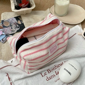 Detail of pink and white striped terry cloth makeup bag with top zipper and soft texture