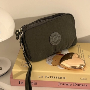 Détail d'une pochette en tissu vert olive avec trois compartiments zippés et dragonne