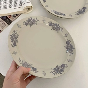 Close-up of stacked ceramic plates with retro blue floral patterns and hand for scale