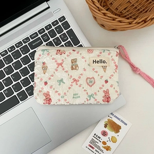 Close-up of quilted cream pouch featuring cute cartoon bear and bunny patterns