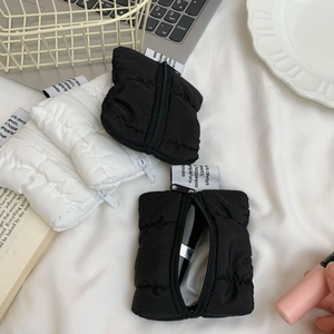 Close-up of quilted puffy mini pouches in black and white with metal zipper and strap