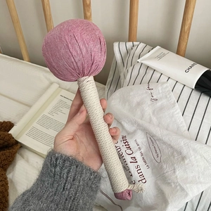 Close-up of pink linen massage hammer held by hand for shoulder and neck meridian relief