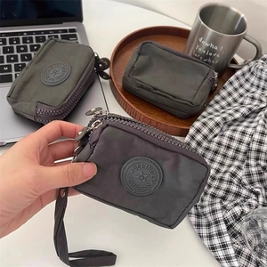 Trois pochettes en toile gris foncé de tailles différentes avec fermeture éclair et dragonne