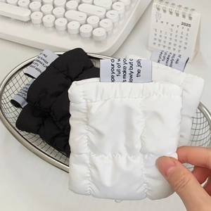 Detail of soft quilted cloud-style mini pouch in white nylon with decorative woven label
