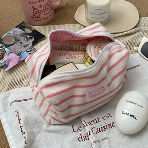 Macro shot of striped terry cloth makeup bag interior filled with various cosmetics
