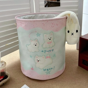 Detail of canvas laundry hamper featuring cute white puppy prints and plush bunny decor