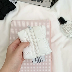 Detailed view of a white quilted down-fabric mini pouch with a zipper and stylish label