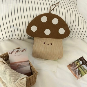 Detail of mushroom tissue box holder with corduroy texture and hanging loop on a bed