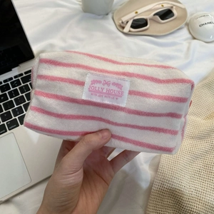 Detail of pink striped towel fabric makeup bag held by hand with brand label