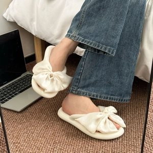 Detail showing silk bow flip flops with soft thick soles in a cozy home setting