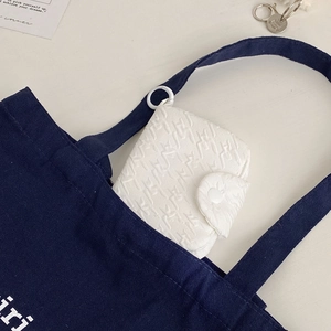 Macro view of white pleated fabric coin purse with round button and hanging ring detail