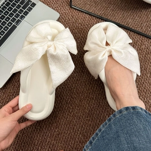 Close-up of white silk bow flip-flops with thick soft soles for summer wear
