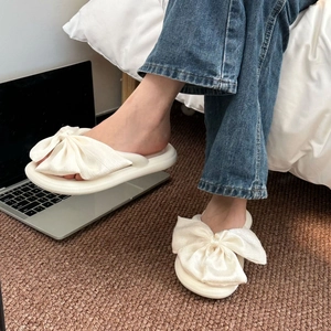 Detail of cream white silk bow flip flops featuring a thick soft sole for home wear
