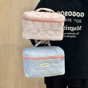 Detailed shot of quilted checkered makeup bags with bow patterns and zipper closure
