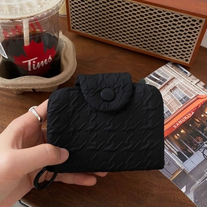 Close-up of a black quilted fabric coin purse with button closure and metal ring