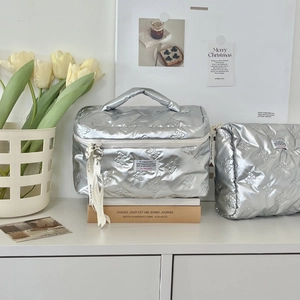 Detailed set of silver quilted bow toiletry bags with ribbon zip on white surface
