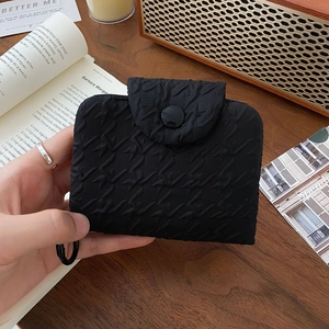 Close-up of black bubble textured fabric coin purse with round button in a retro setting
