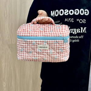 Quilted red and white gingham makeup bag with blue bow patterns and blue zipper