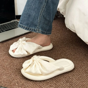 Detail of white silk bow flip-flops with soft thick sole in a lifestyle setting