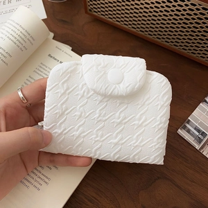 Detail of white textured puff fabric coin purse with button closure in a vintage setting