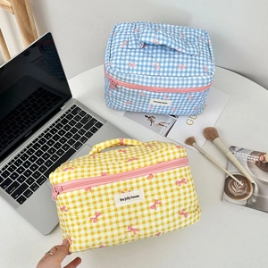 Quilted checkerboard makeup bags in blue and yellow with pink bow patterns and handles