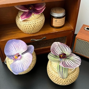 Close-up of bamboo storage boxes with lifelike orchids on a stylish wooden desk