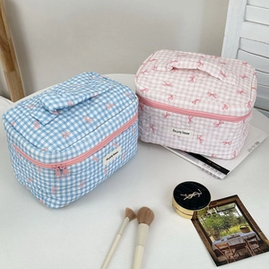 Detail of quilted plaid cosmetic bags with pink bow print and sturdy fabric handles
