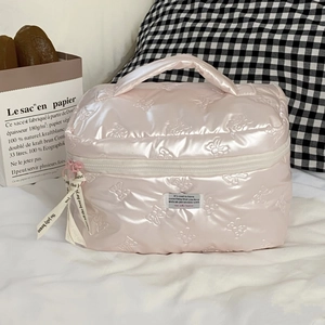 Detail einer rosa Kosmetiktasche mit Schmetterlingsprägung und Bandanhänger